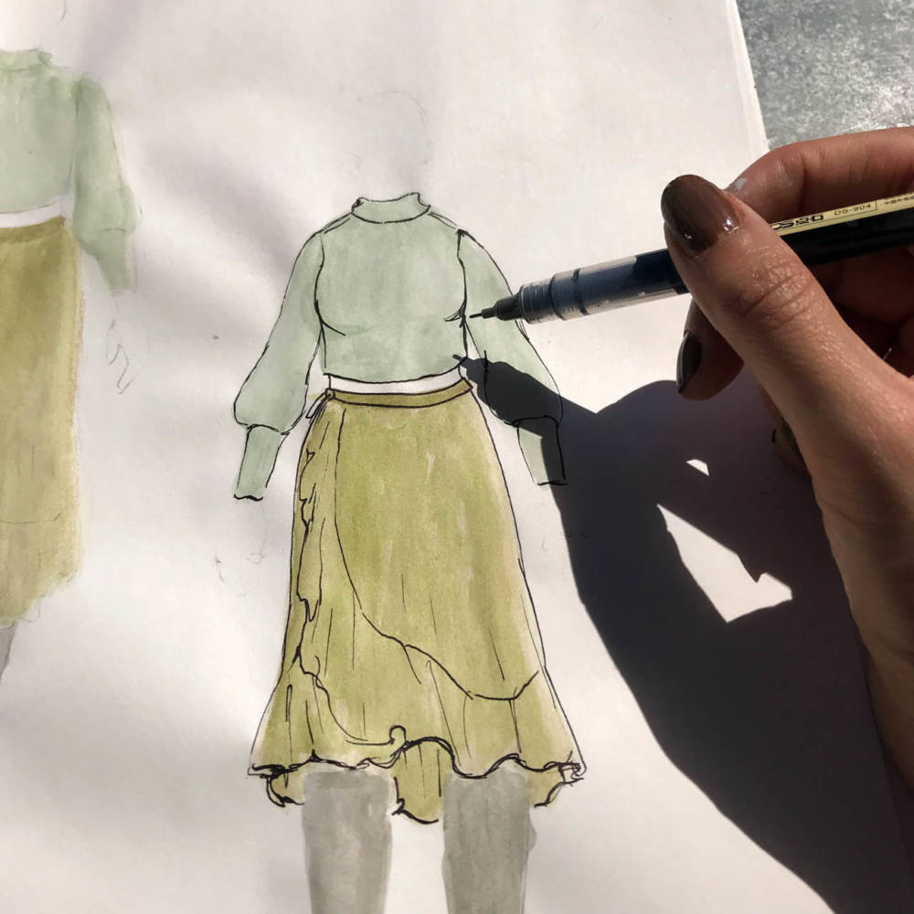 Amanda uses a fine line pen over her colored MyBodyModel croquis sketches to add depth and detail. Pictured is her drawing over a sketch of a green Frankie skirt and matching green sweater from her closet.