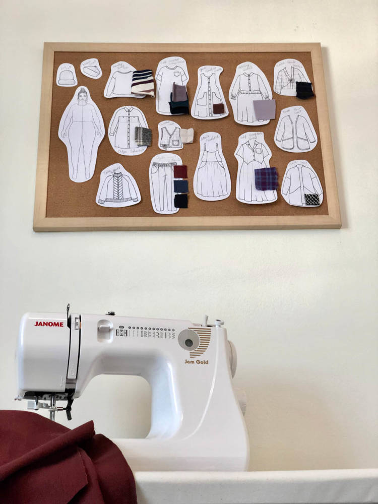 Sarah's seasonal sewing & knitting corkboard with fabric swatches and paper cutouts and drawings of her MyBodyModel croquis and wardrobe plans on the wall above her sewing machine.
